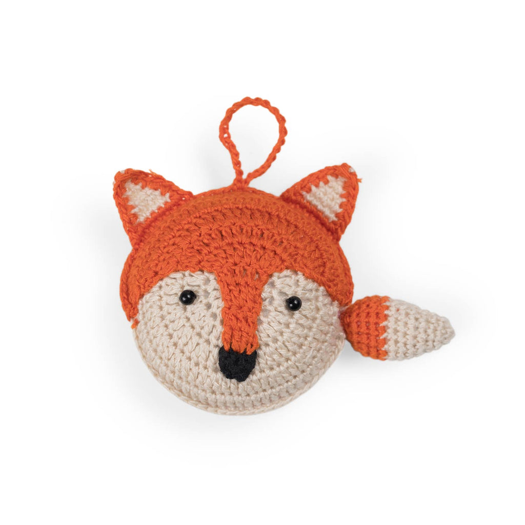 A hand-crocheted cotton measuring tape cover designed to look like a fox's head, with orange and beige colors.