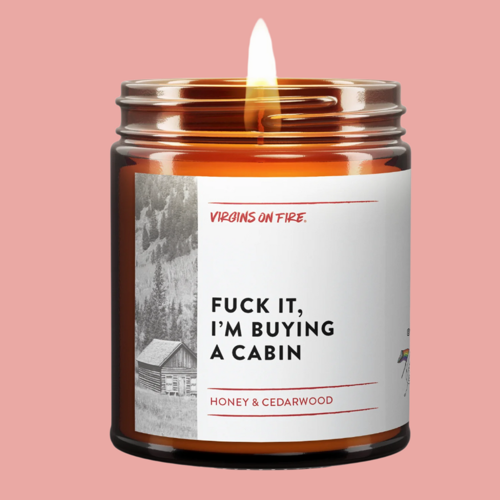 candle with label "fuck it im buying a cabin"  with honey + cedarwood smell